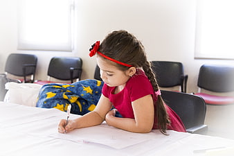 Little girl drawing at a table in a classroom