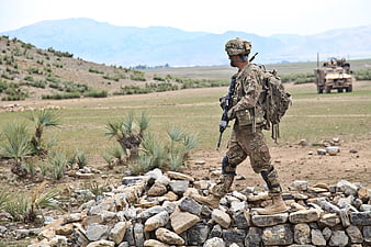 Soldier on Patrol in Arid Landscape with Military Vehicle