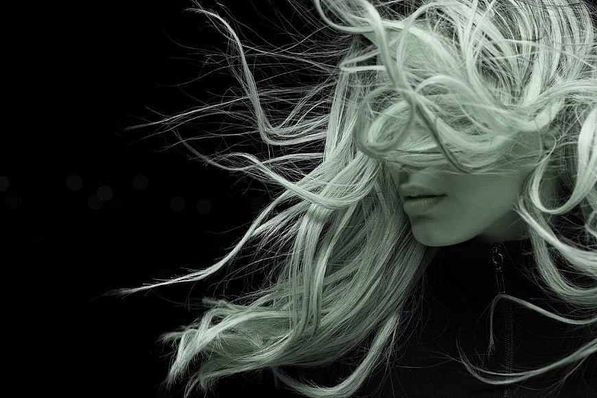 Dramatic Portrait of Woman with Windblown Hair Against Black Background
