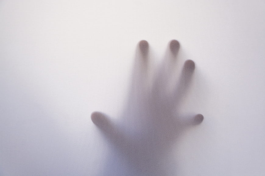 Blurry hand silhouette behind frosted glass