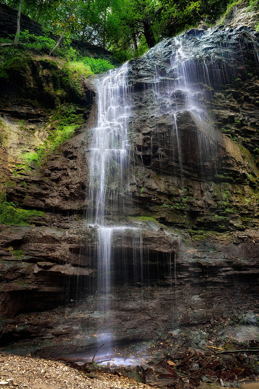Tall waterfall cascading down rocky cliff in lush forest