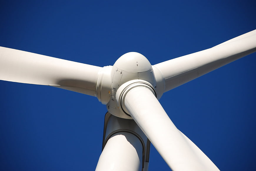 Low angle view of white wind turbine blades against blue sky
