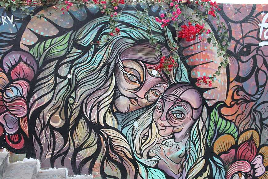 Colorful street art mural of witches with flowers in Lima