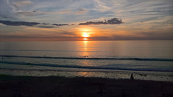 Serene Sunset Over Ocean with Surfers Silhouettes