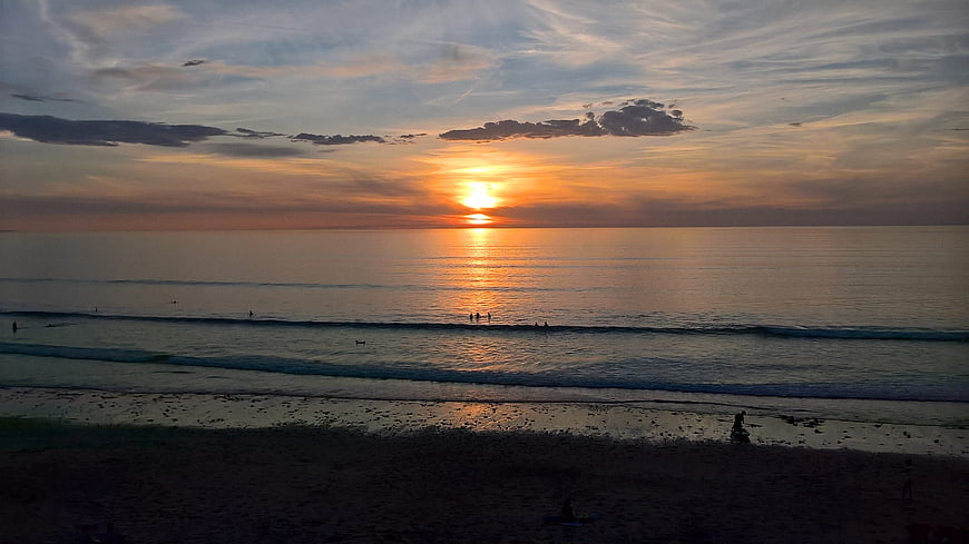 Serene Sunset Over Ocean with Surfers Silhouettes