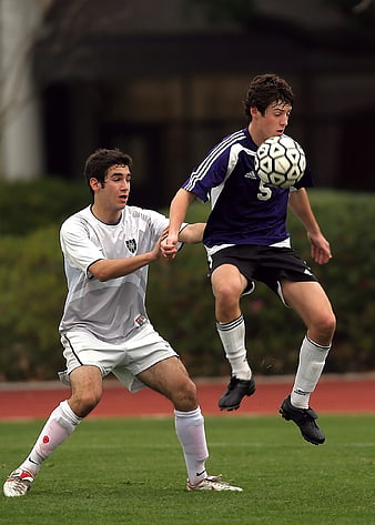 Two Soccer Players Competing for the Ball on a Grass Field