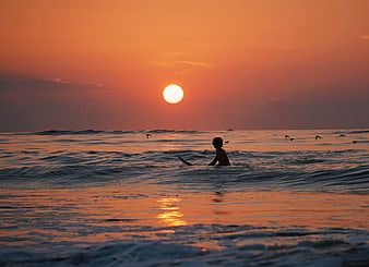Silhouette of Surfer in Ocean at Golden Sunset