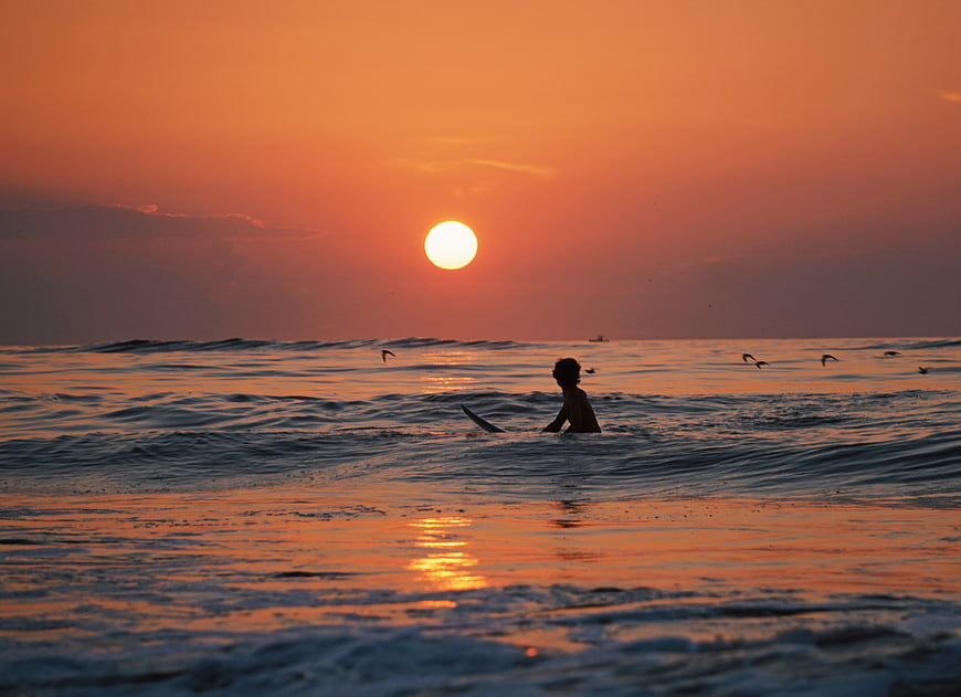 Silhouette of Surfer in Ocean at Golden Sunset