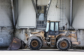 Yellow Caterpillar Wheel Loader Parked Against Industrial Wall