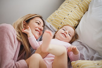 Happy mother and baby playing together in bed