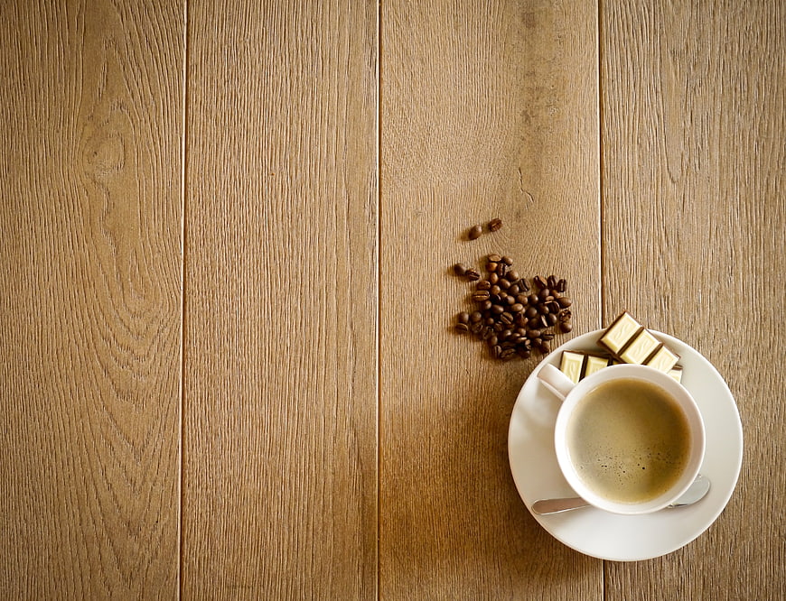 Coffee cup with beans and chocolate on wooden surface