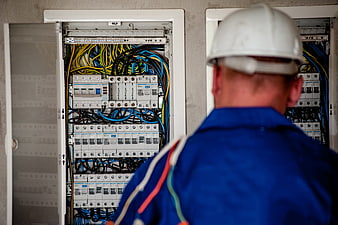 Electrician inspecting open electrical panel with colorful wires