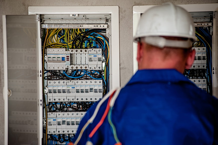 Electrician inspecting open electrical panel with colorful wires
