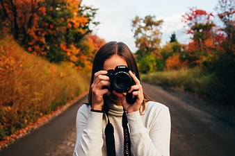 Woman photographer taking photo on autumn road