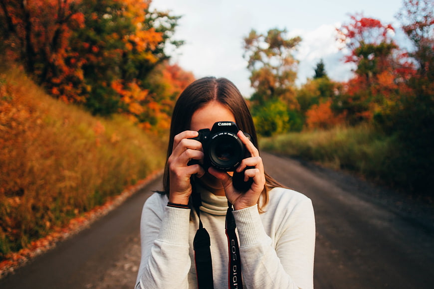 Woman photographer taking photo on autumn road