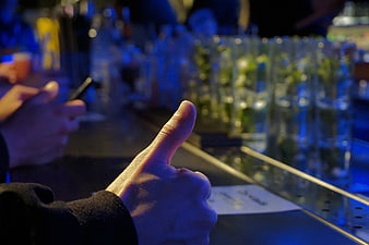 Thumbs Up Gesture at Bar with Blue Lighting
