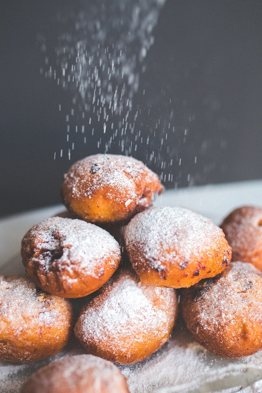 Powdered sugar falling on golden fried donuts
