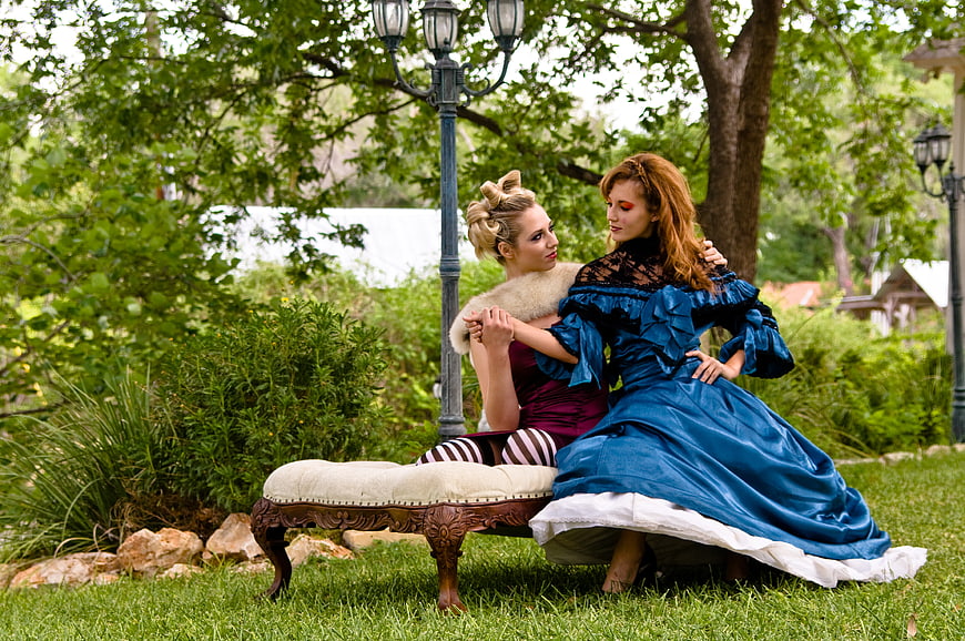 Two Women in Vintage Dresses Sitting on Garden Bench