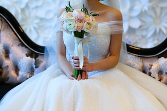 Bride holding pastel rose bouquet in white wedding dress