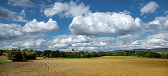 Panoramic rural landscape with golden field and dramatic clouds