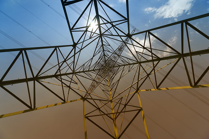 Low angle view of high voltage electricity pylon against blue sky