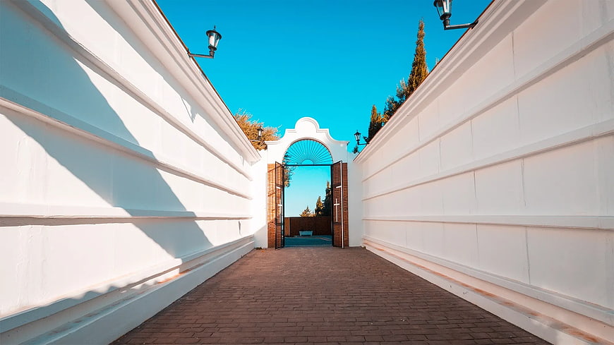 Symmetrical White Walled Pathway Leading to Open Gate