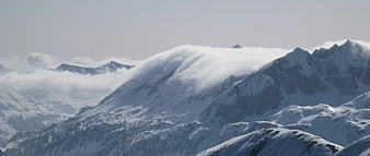 Snowy Mountain Peaks with Flowing Clouds in Winter