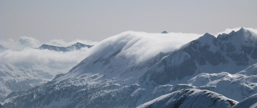 Snowy Mountain Peaks with Flowing Clouds in Winter