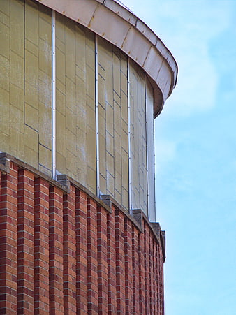 Curved Brick and Concrete Building Facade Against Blue Sky