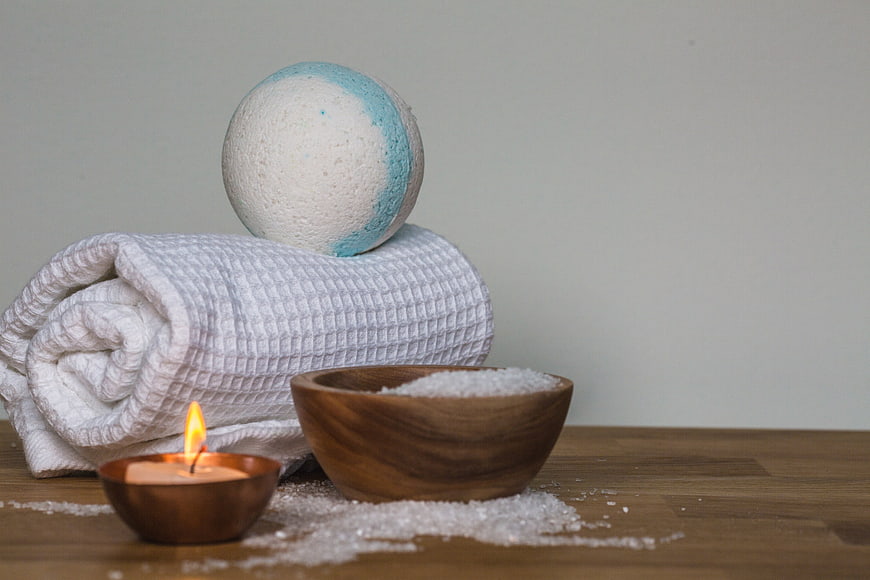 Spa bath bomb, candle, and salt on wooden table