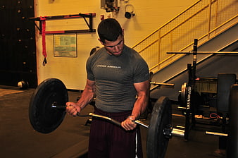 Athletic man performing barbell row in gym