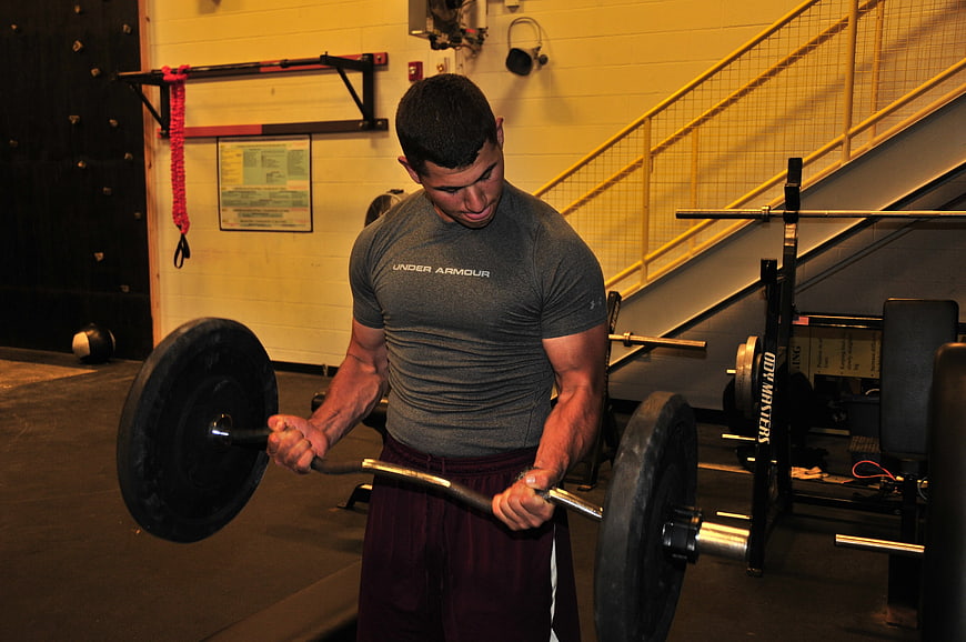 Athletic man performing barbell row in gym