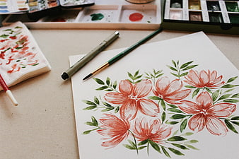 Watercolor floral painting with art supplies on desk
