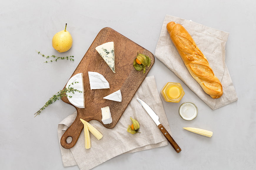Top view of cheese platter with baguette and honey