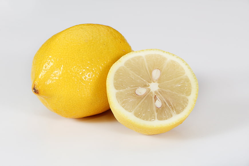 Fresh whole and sliced lemon on white background