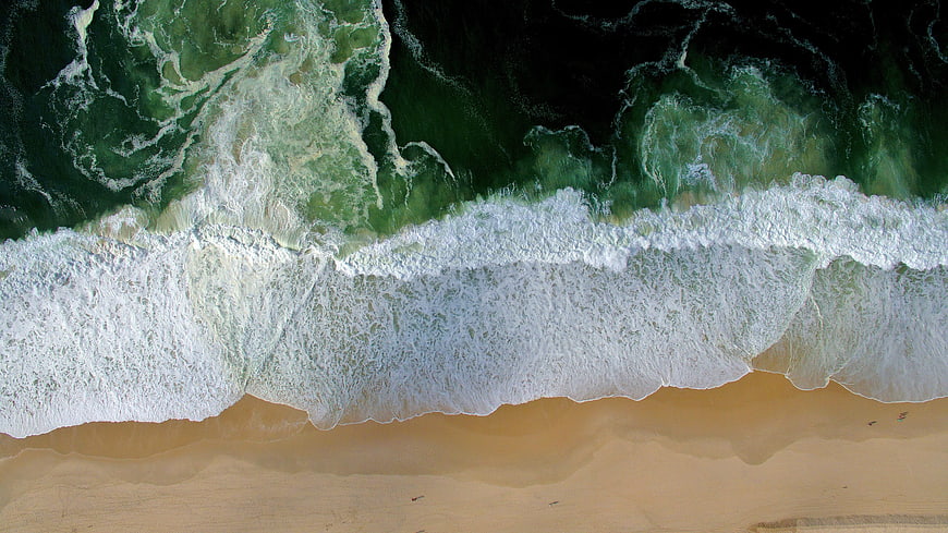 Aerial View of Ocean Waves Crashing on Sandy Beach