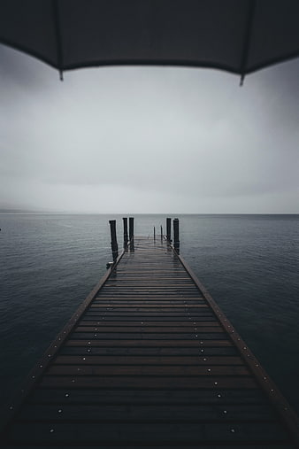Wooden pier extending into calm ocean under rainy umbrella