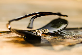 Close-up of black sunglasses on wet wooden surface