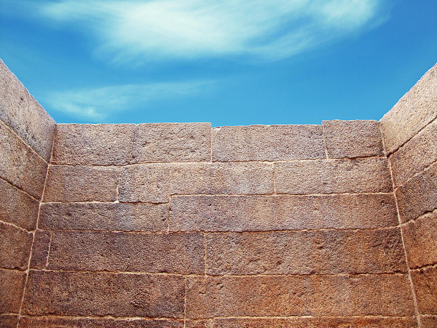 Ancient stone wall corner against blue sky