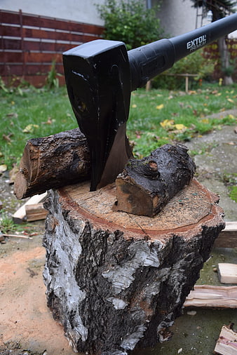 Black axe splitting wood on tree stump outdoors
