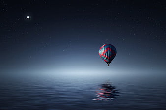 Hot Air Balloon Floating Over Calm Ocean at Night