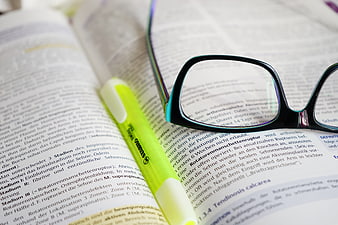 Reading glasses and highlighter on open medical textbook