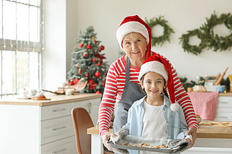 Grandmother and granddaughter baking Christmas cookies in festive kitchen