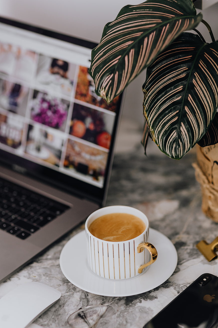 Modern workspace with coffee, laptop, and plant