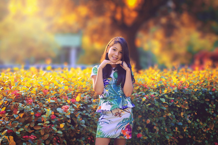 Smiling Girl in Tropical Dress Standing in Autumn Garden