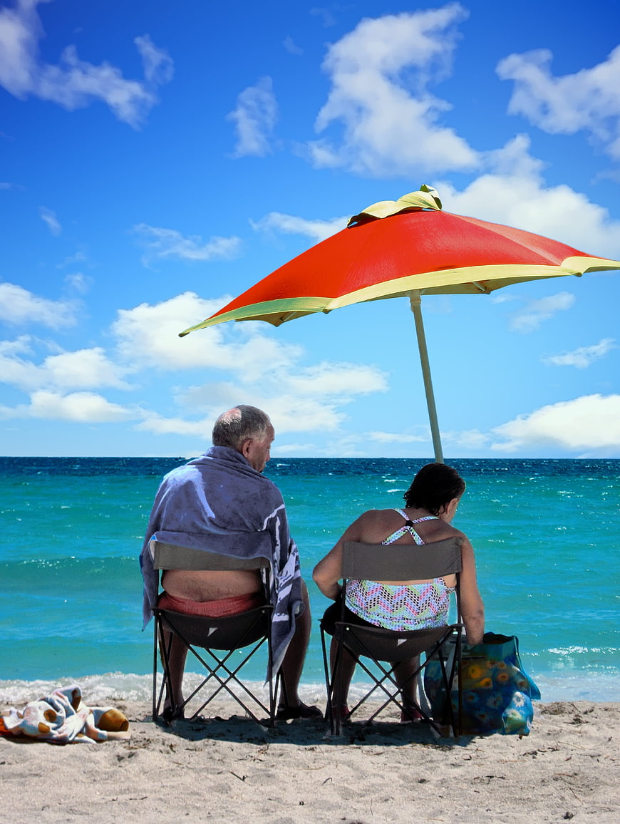 Senior couple relaxing under beach umbrella