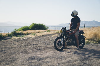 Man on Vintage Motorcycle on Dirt Road by Sea