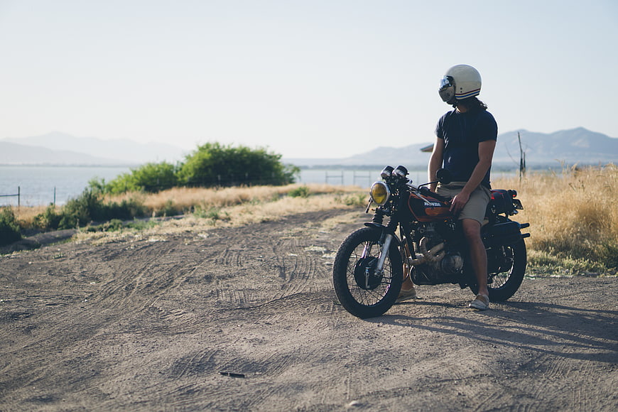 Man on Vintage Motorcycle on Dirt Road by Sea