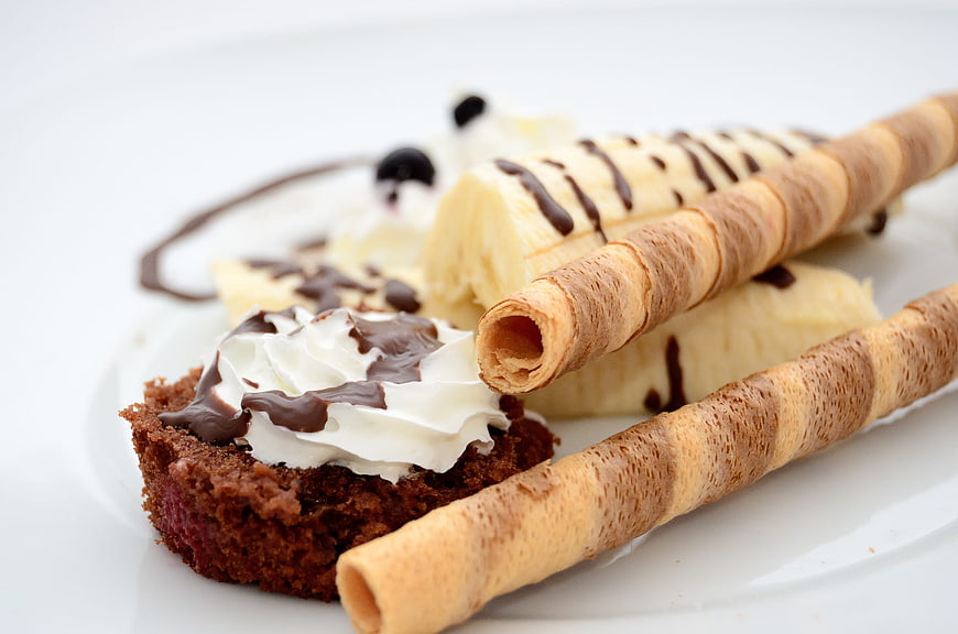Chocolate brownie with whipped cream, banana, and wafer rolls