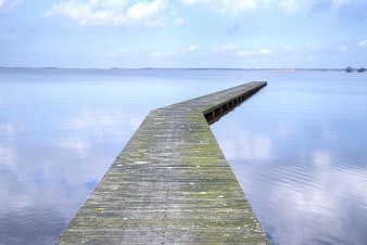 Serene wooden pier extending into calm blue lake water